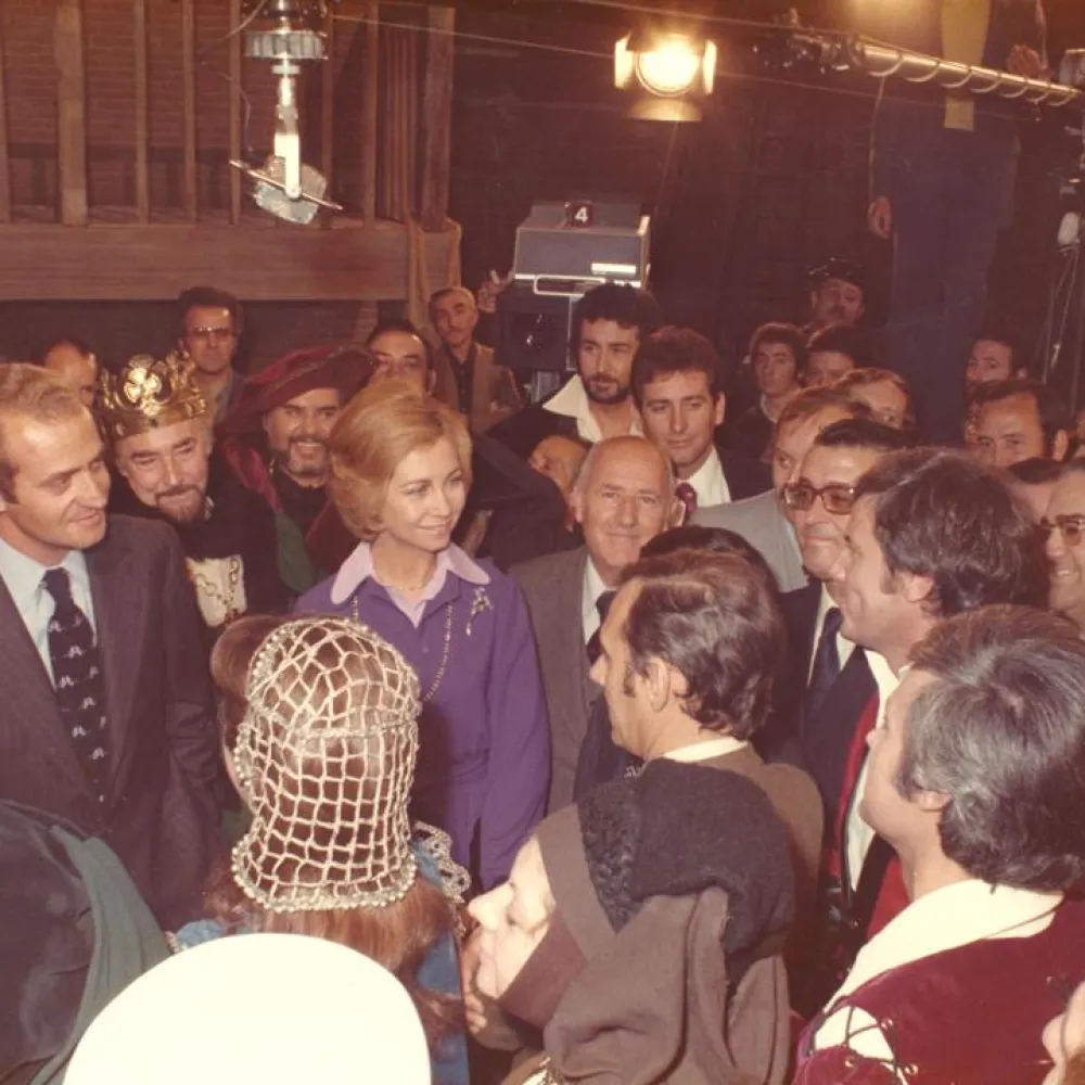 Sus Majestades los Reyes visitan Prado del Rey y hablan con los actores que están grabando en los estudios. Paco Valladares, con barba, en el centro, al fondo. 